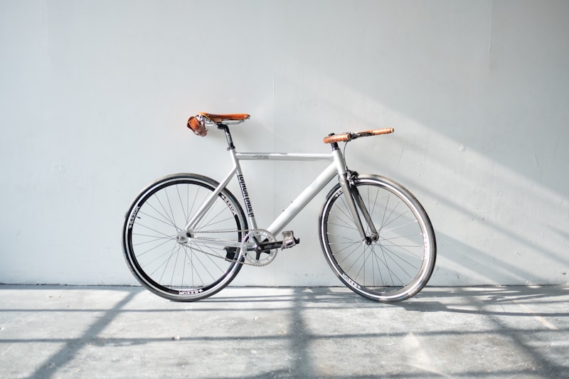 Silbernes Urban-Bike mit braunem Ledersattel und Griffen an einer weißen Wand